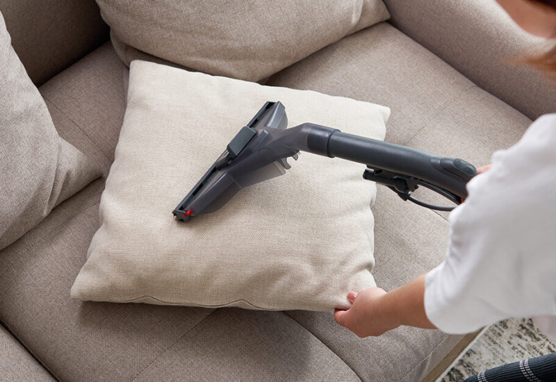 young-housewife-cleaning-sofa-with-vacuum-cleaner-living-room